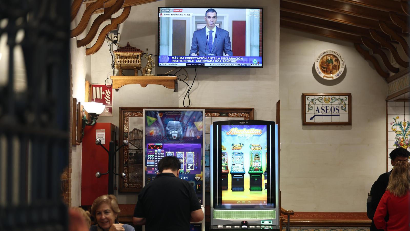 Several people follow the appearance of Pedro Sánchez in a bar