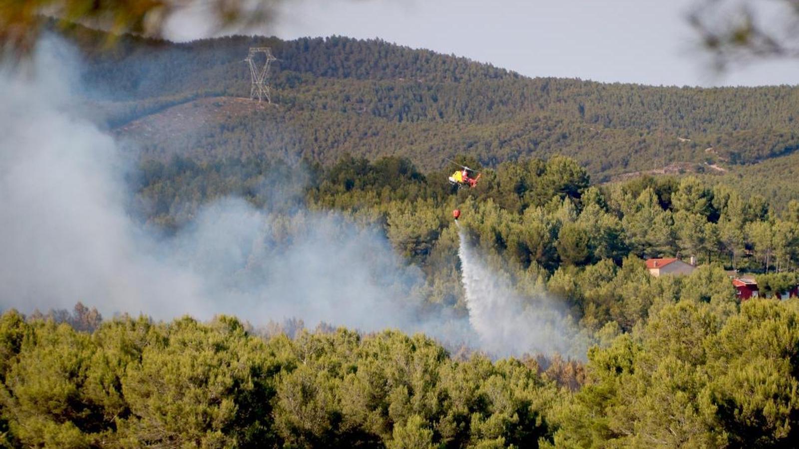 A helicopter unloads water on the Pla de Manlleu fire