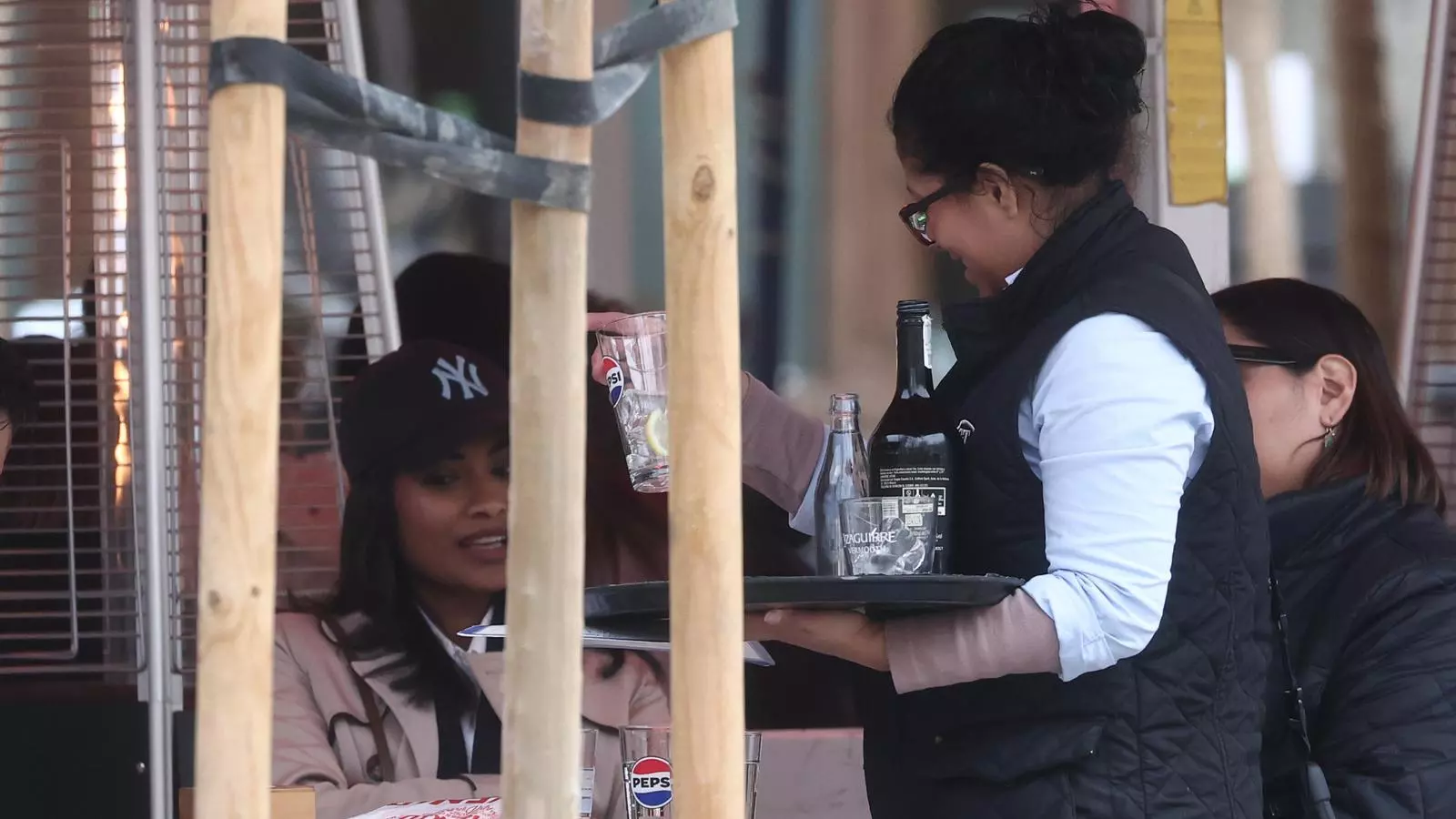 Una cambrera atenent clients a una terrassa.