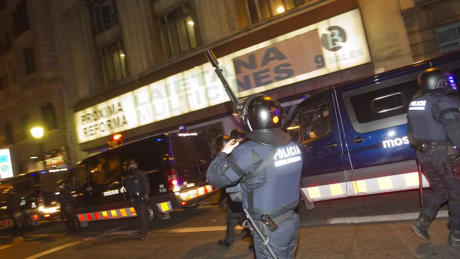 Un mosso amb una escopeta per llançat pilotes de goma davant del cinema ocupat. / JORDI PIZARRO