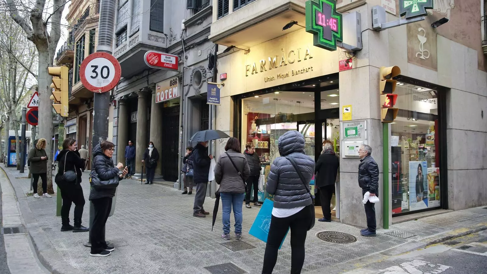 Cua mantenint la distància per entrar a comprar en una farmàcia de Sabadelll