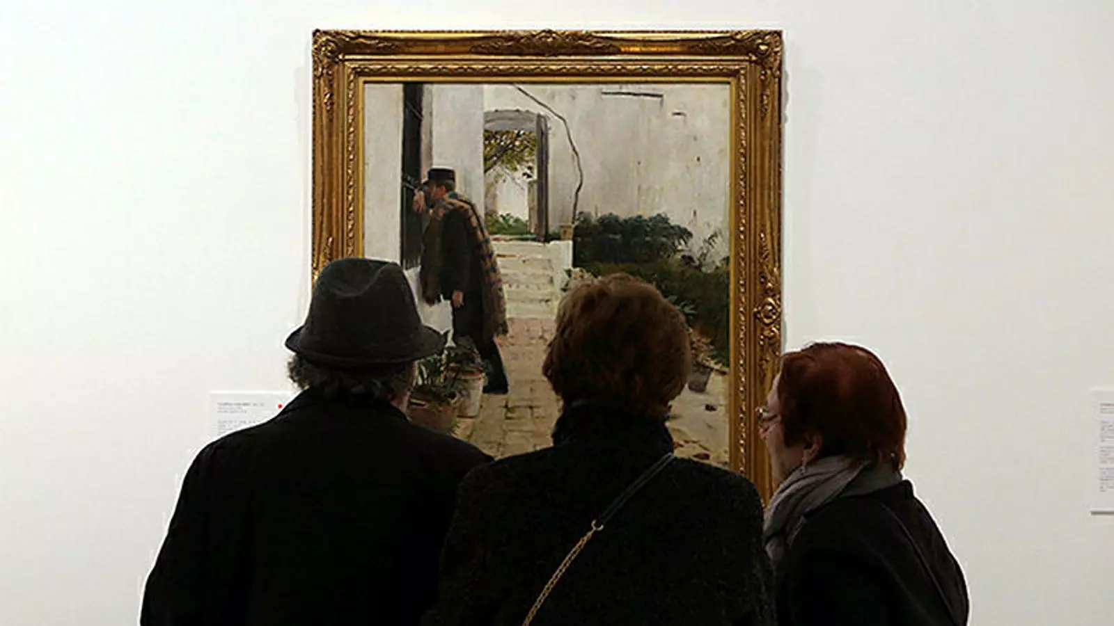 Tres visitants de l'exposició miren el quadre de Santiago Rusiñol 'Pelando la pava'