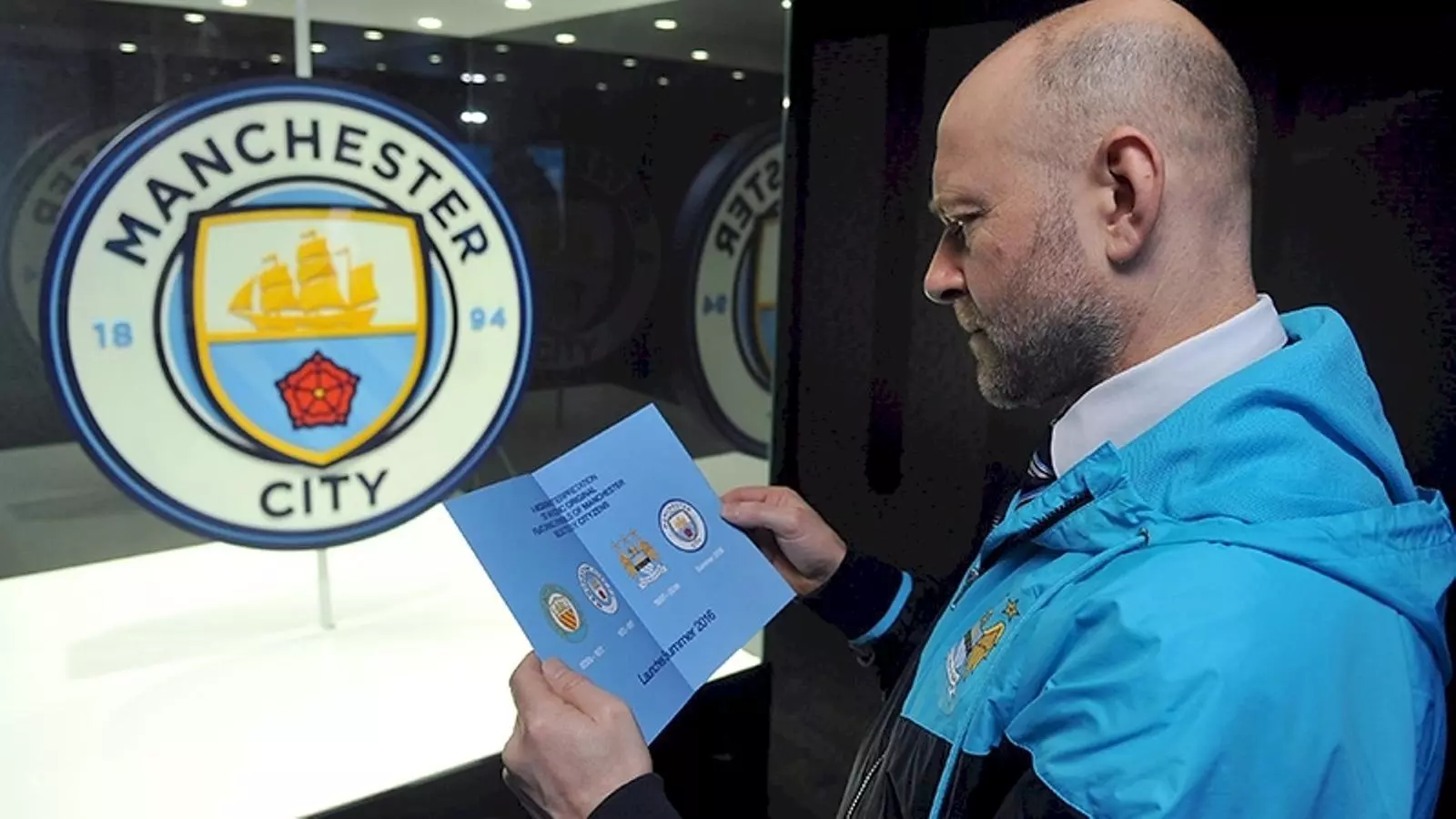 Un seguidor del Manchester City observa l'evolució històrica de l'escut
