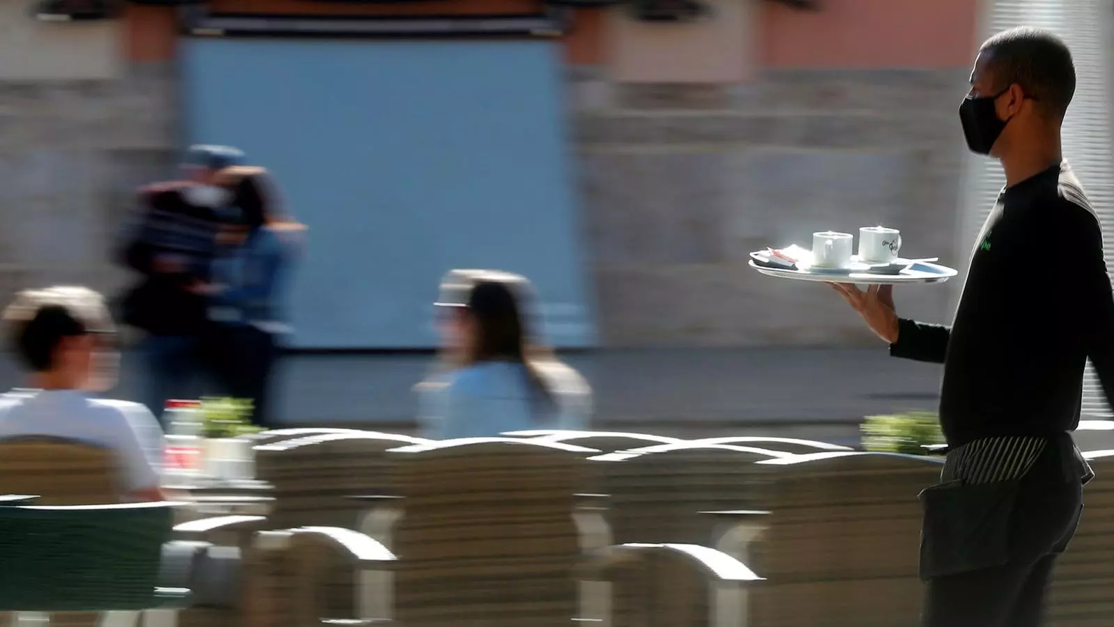 Un cambrer atén uns clients en una terrassa a la ciutat de València