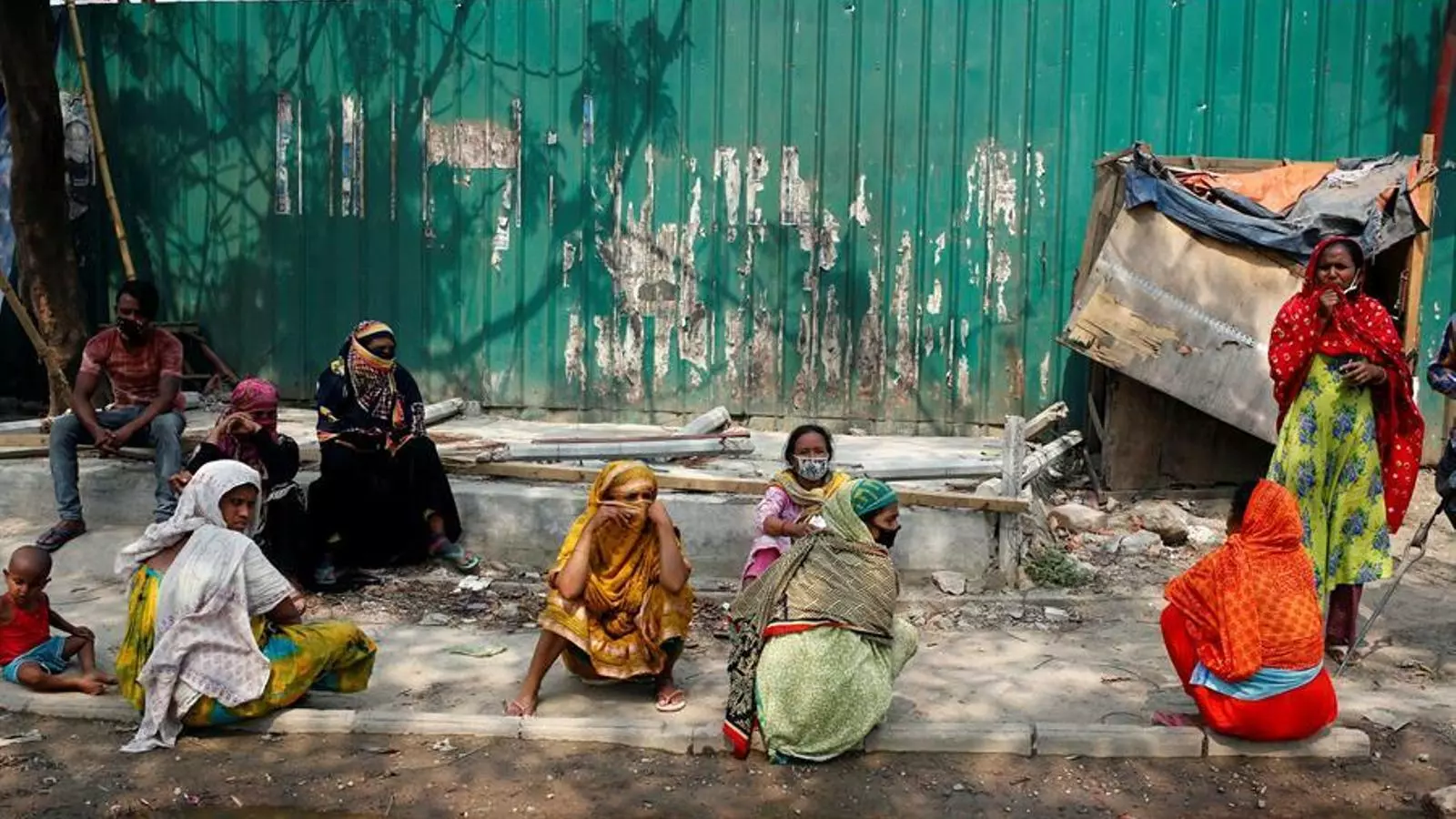 Un grup de dones assegudes en la vorera d'un carrer de Dhaka, la capital de Bangladesh, en mig del confinament decretat fins el 25 d'abril