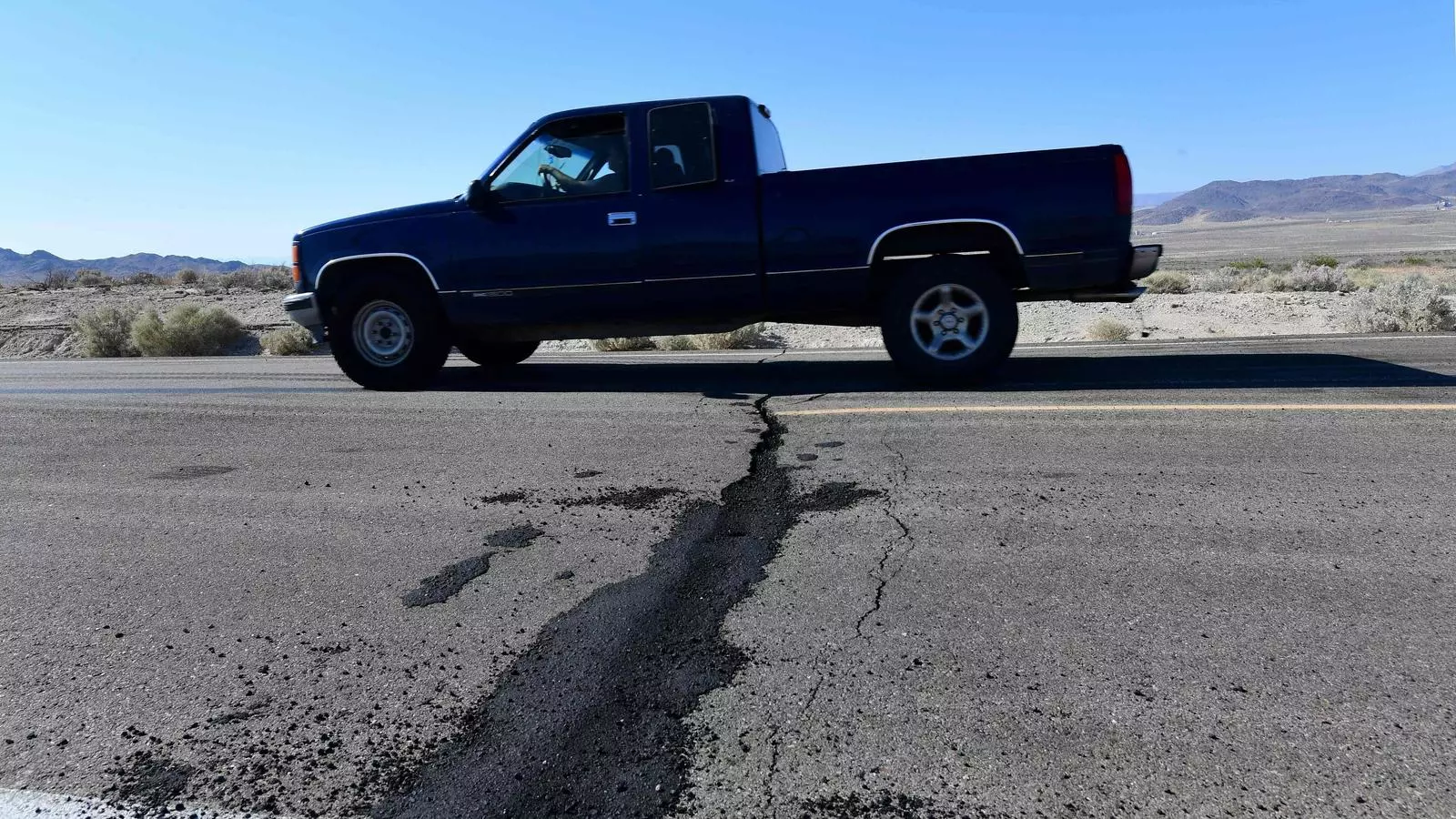 Un cotxe circula per una carretera propera a la ciutat de Ridgecrest, al sud de Califòrnia, que presenta una gran esquerda a causa dels sismes que han sacsejat la zona des de dijous