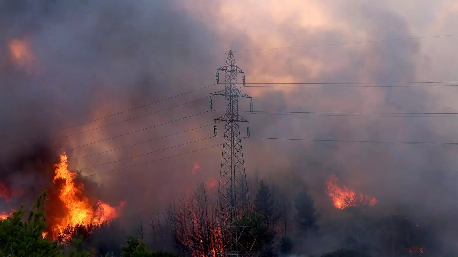 El foc crema davant una torre elèctrica a Varimbombi, nordest de la regió d'Àtica, a les perifèries d'Atenes
