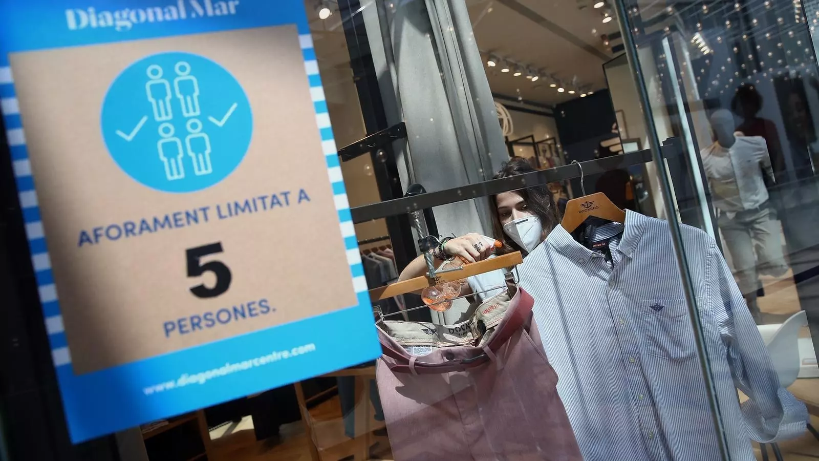 Una dependenta desinfectant una botiga del centre comercial Diagonal Mar