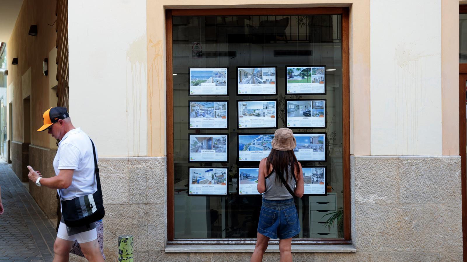 Una chica mira precios de viviendas en una inmobiliaria de Palma.