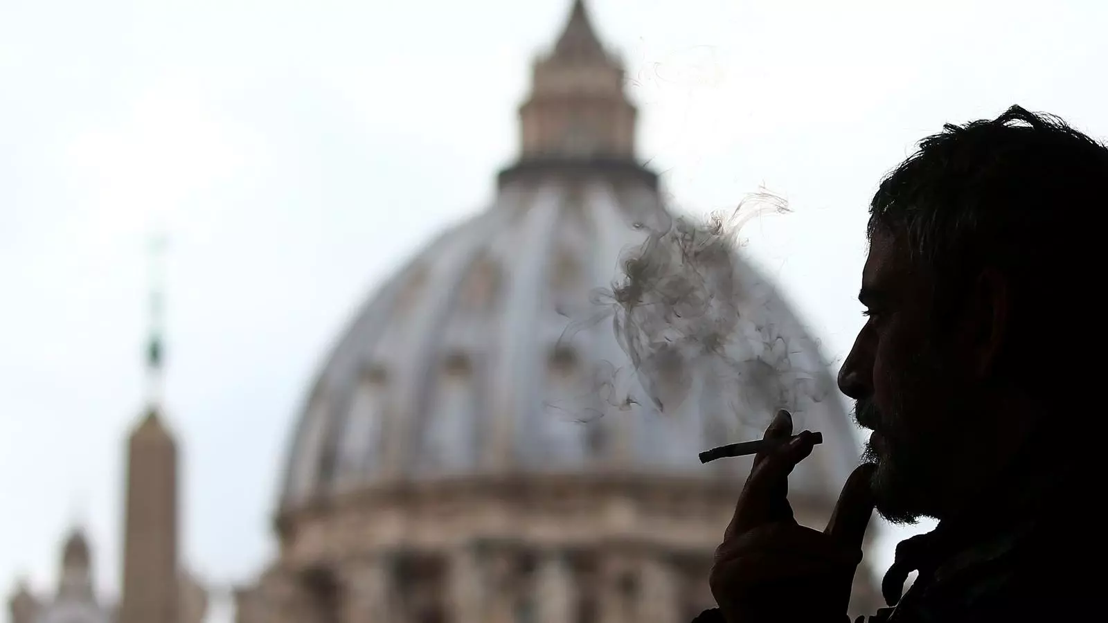Un home fuma amb la cúpula de la Basílica de Sant Pere del Vaticà al fons, aquest dijous 9 de novembre