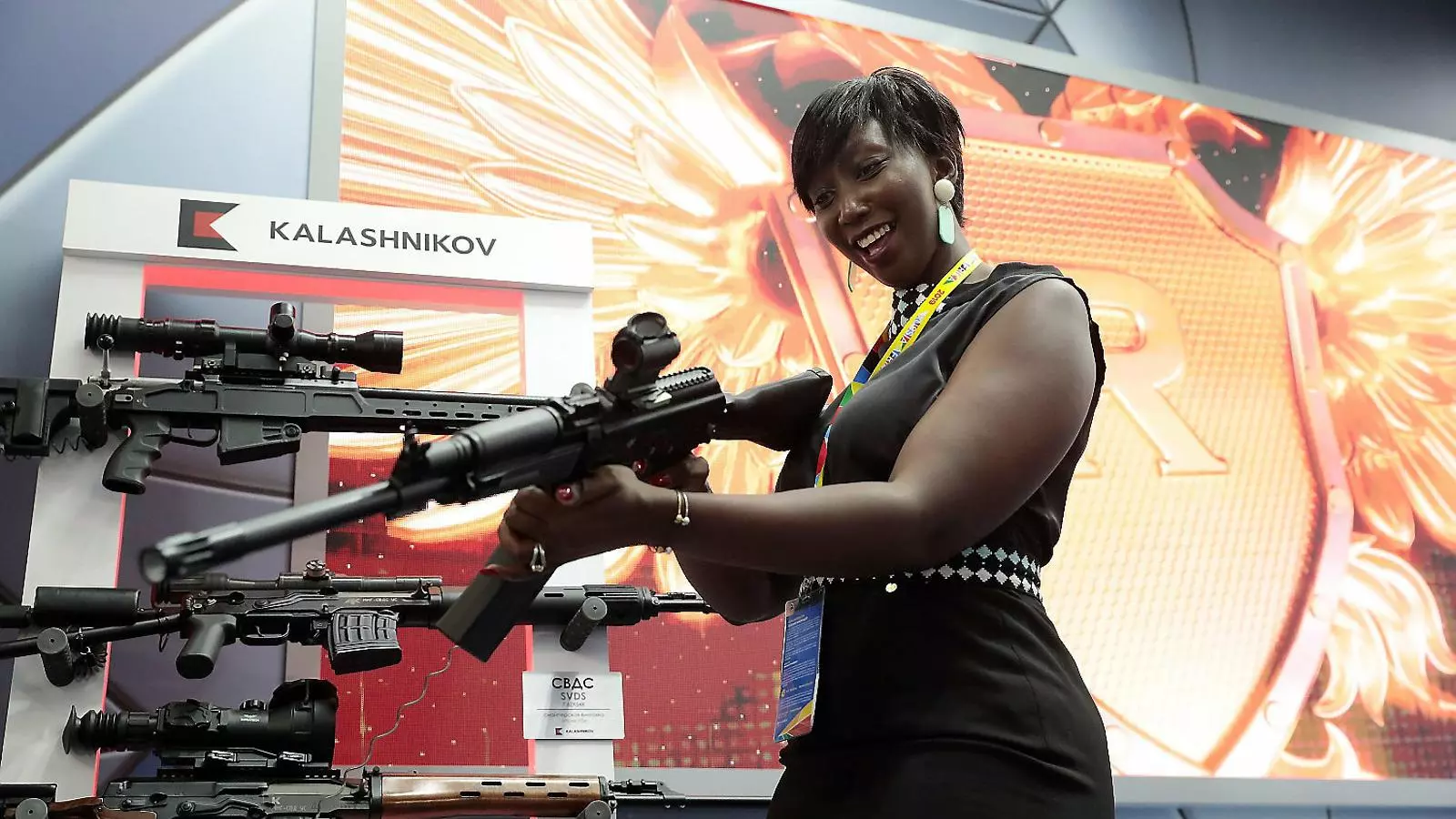 Una delegada africana somriu mentre prova un dels Kalàixnikovs en venda a la cimera de Sotxi.