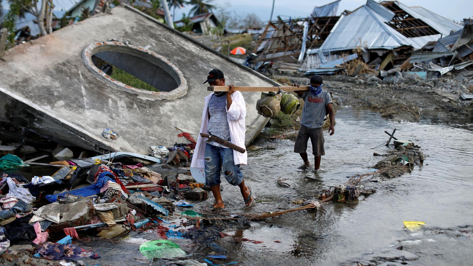 Dos homes caminen entre les destrosses causades pel sisme i el posterior tsunami de fa gairebé dues setmanes a Palu.