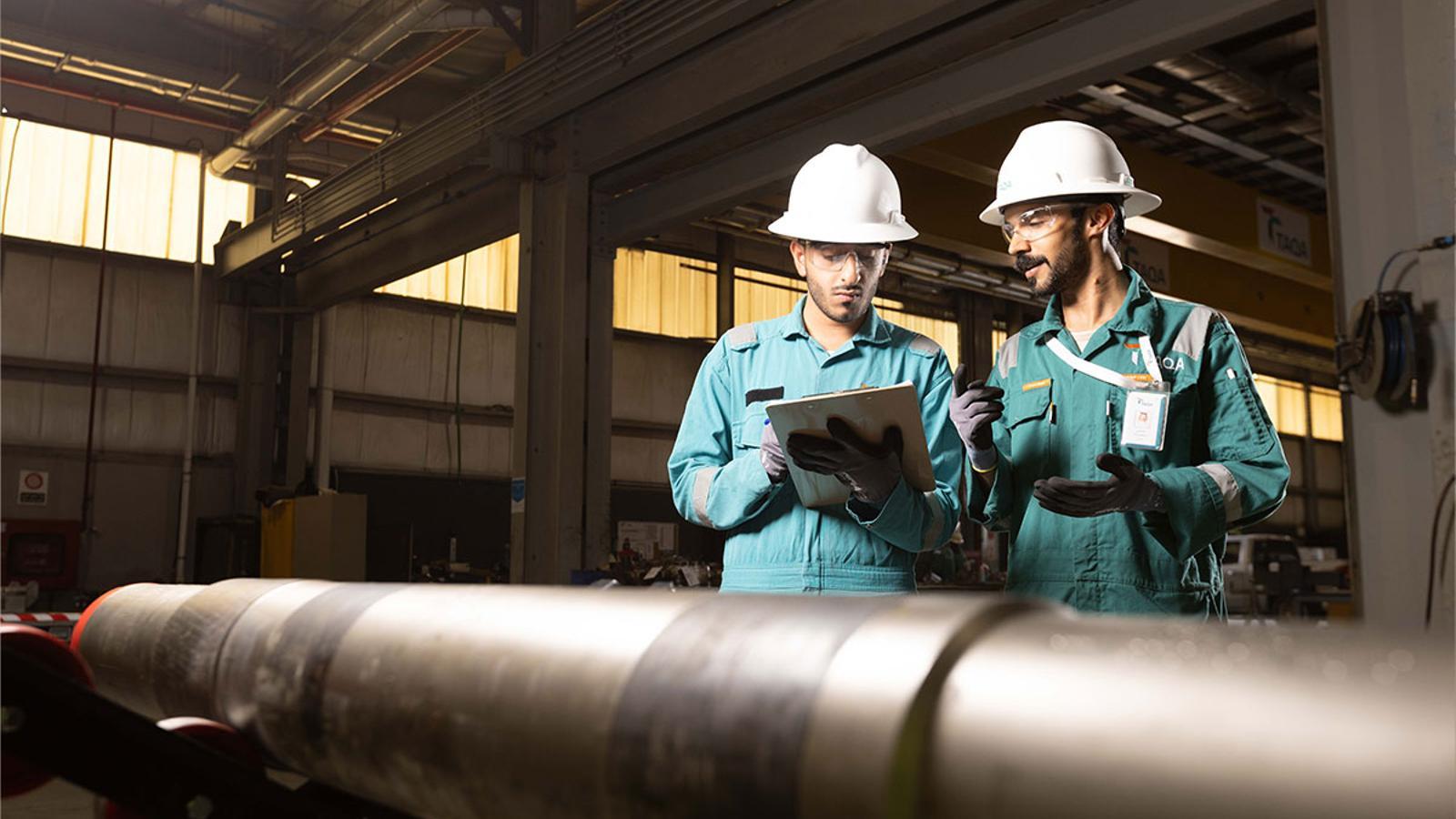 Two Taqa workers, with a pipe in front of them