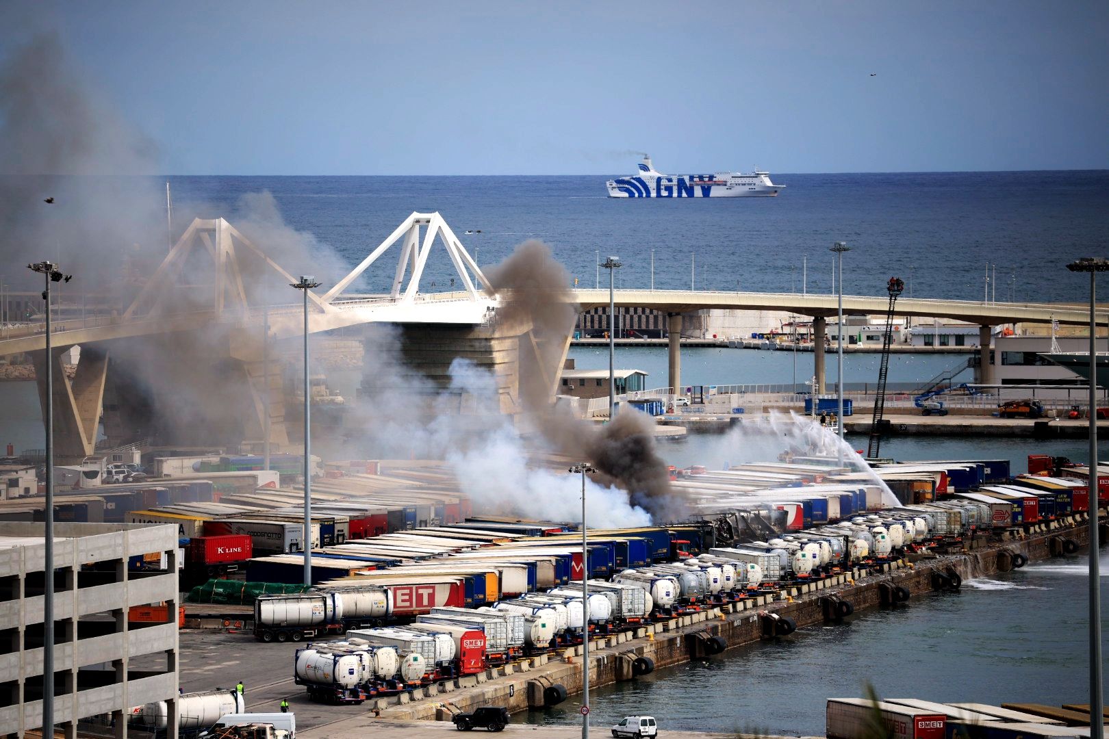 Els bombers treballen per apagar un incendi a la zona del port de Barcelona.