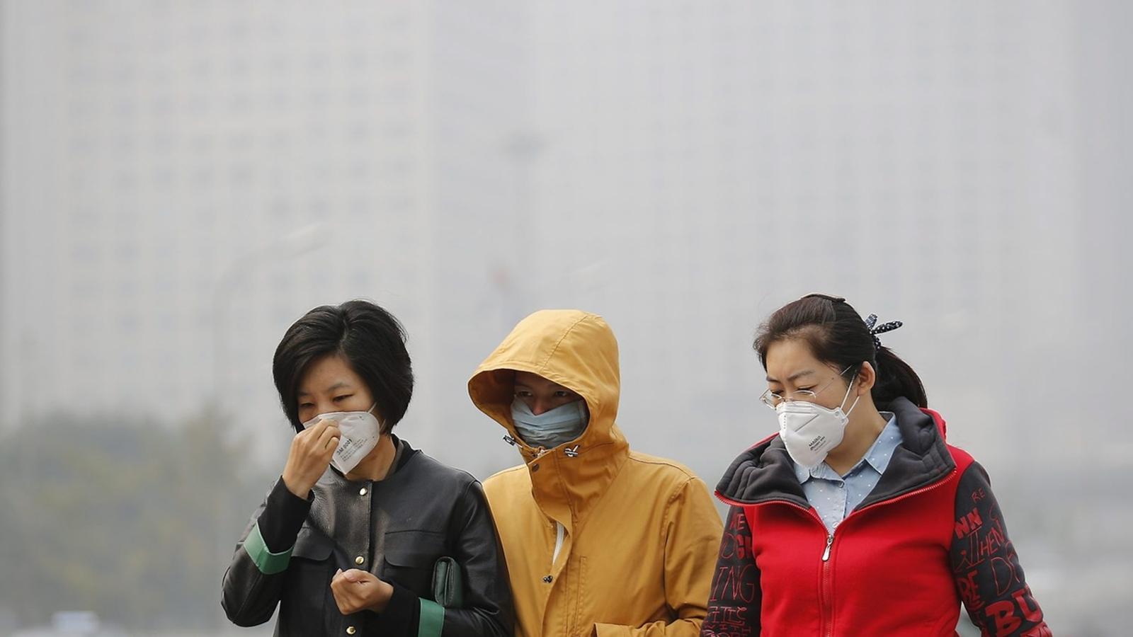 EL PERILL DE RESPIRAR Segons dades oficials, la contaminació a la Xina provoca fins a 500.000 morts prematures cada any. A la imatge, tres dones passegen amb mascaretes a Pequín per protegir-se del boirum (barreja de boira i fum) que inunda la ciutat.
