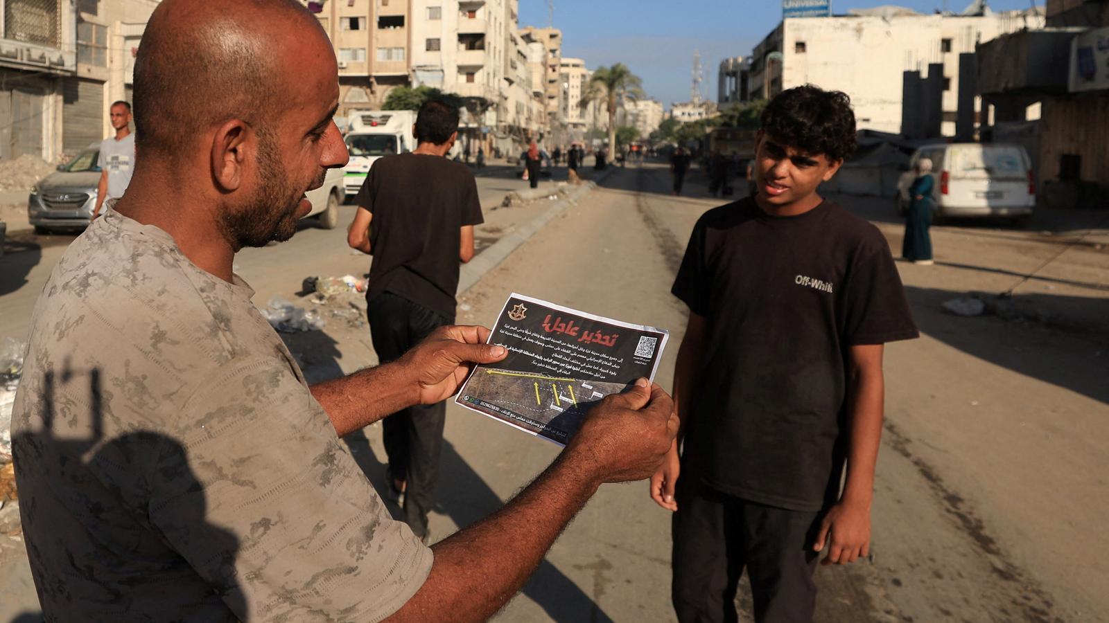 A Palestinian man holds a leaflet, airdropped by Israeli forces, ordering Gaza City residents to evacuate.