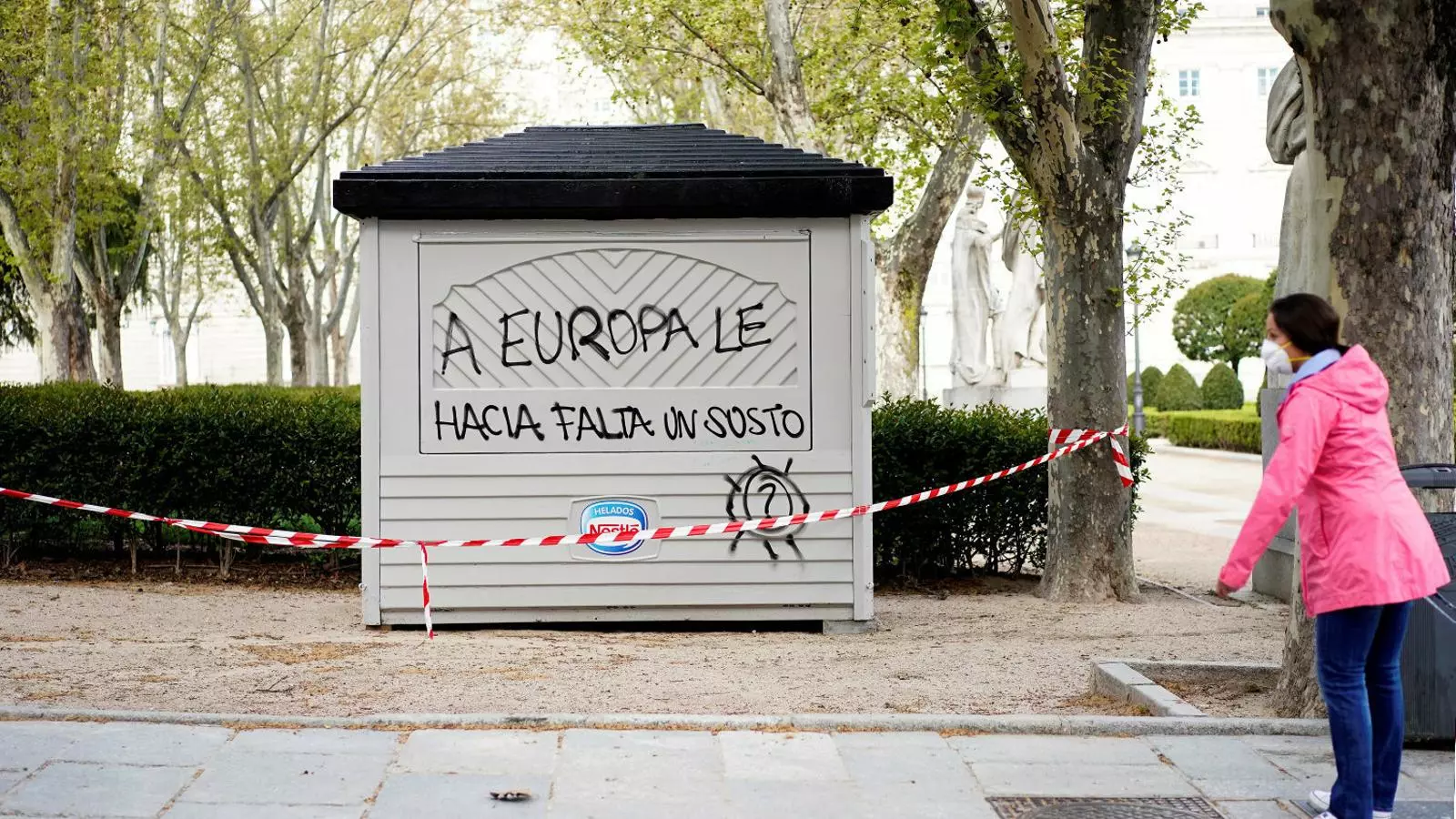Una dona amb una màscara protectora davant un quiosc tancat en una plaça de Madrid. Els ministres de Finances de l’eurozona es reuneixen avui per intentar aprovar el primer escut econòmic davant la crisi del coronavirus.