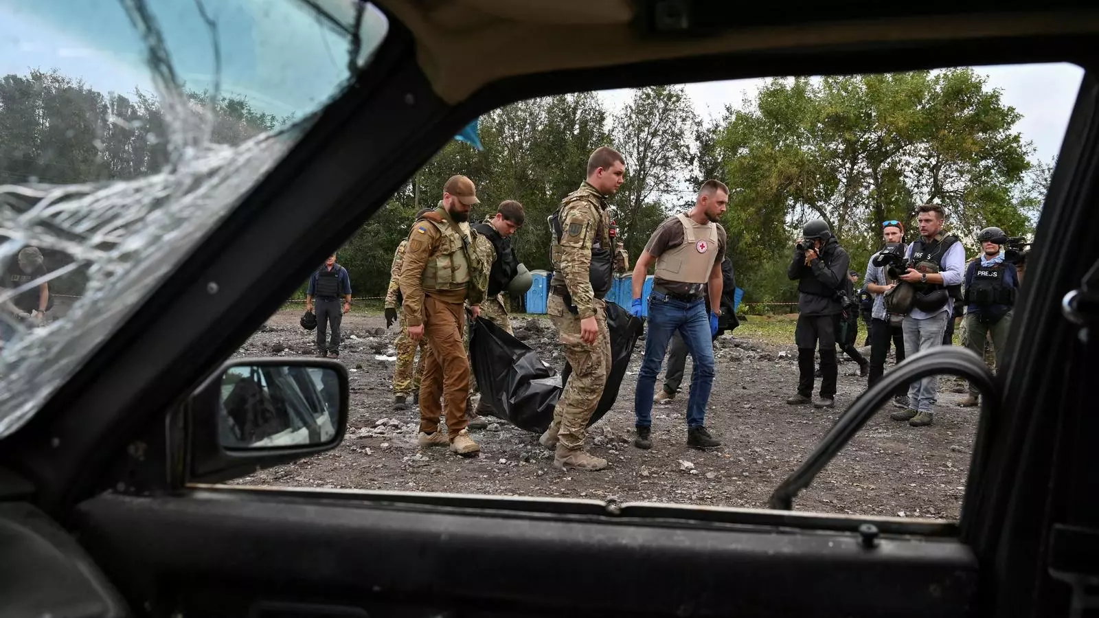Agentes de policía traen el cuerpo cubierto de una persona muerta por un ataque con misiles rusos contra un convoy de vehículos civiles aprop de Zaporizhzhia, en Ucrania.