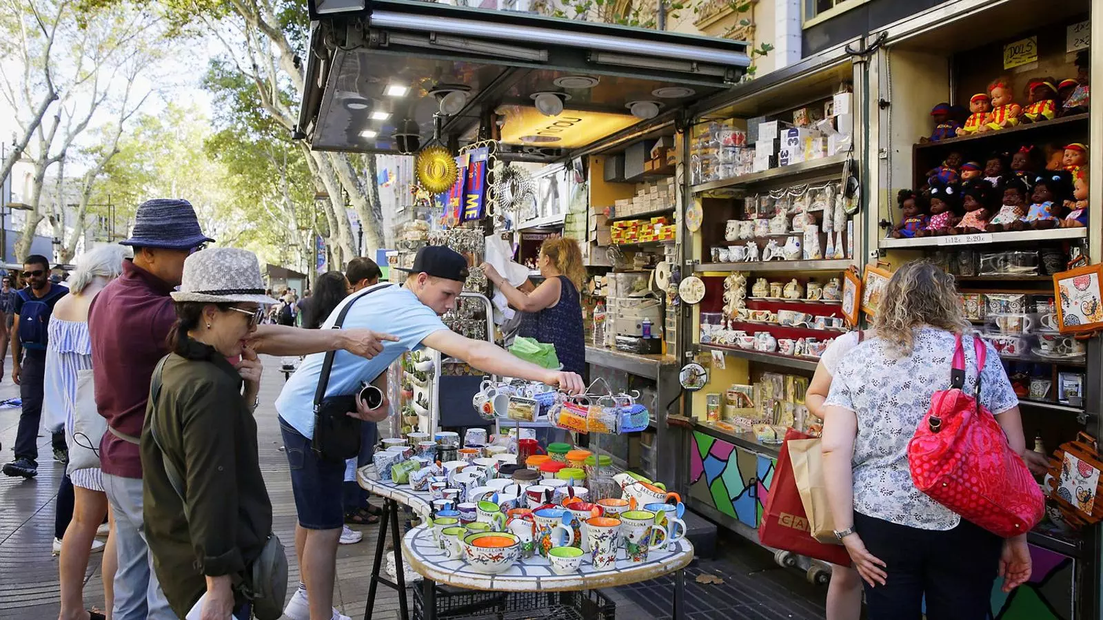 Turistes mirant els productes d’una de les parades de souvenirs de la Rambla de Barcelona.