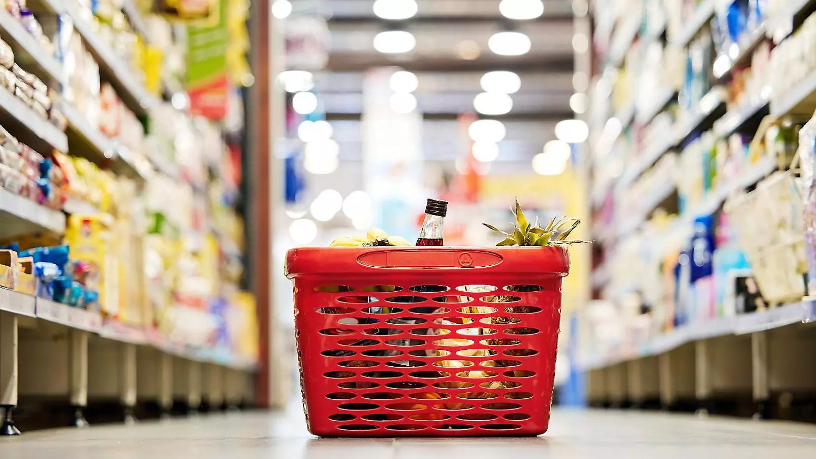 Imatge d’un cistell en un supermercat amb aliments bàsics a l’interior.