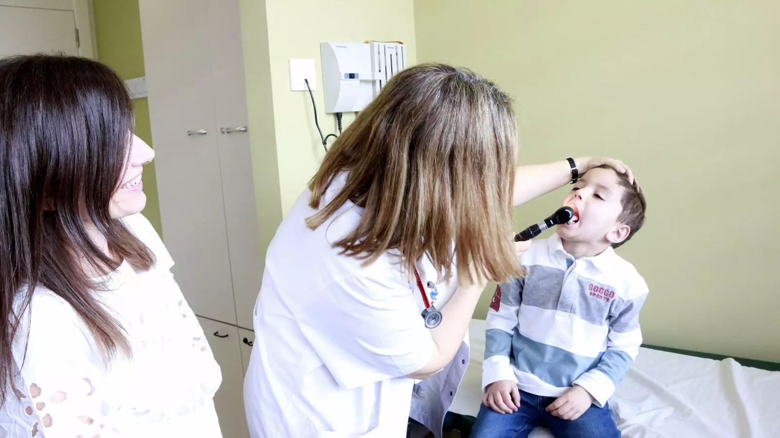La doctora Susana Rives explora l'Álvaro, el primer pacient pediàtric que ha estat tractat amb la teràpia CAR-T 19 finançada pel Ministeri de Sanitat, acompanyat per la seva mare, Marina, a l'Hospital Sant Joan de Déu.