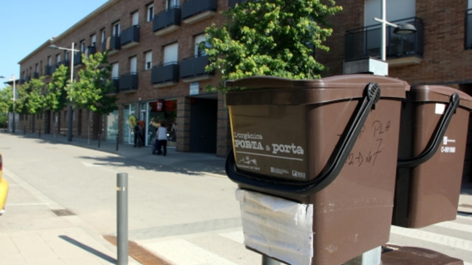 Cubells per a la recollida de la fracció orgànica penjats al davant d'un bloc d'habitatges de Celrà