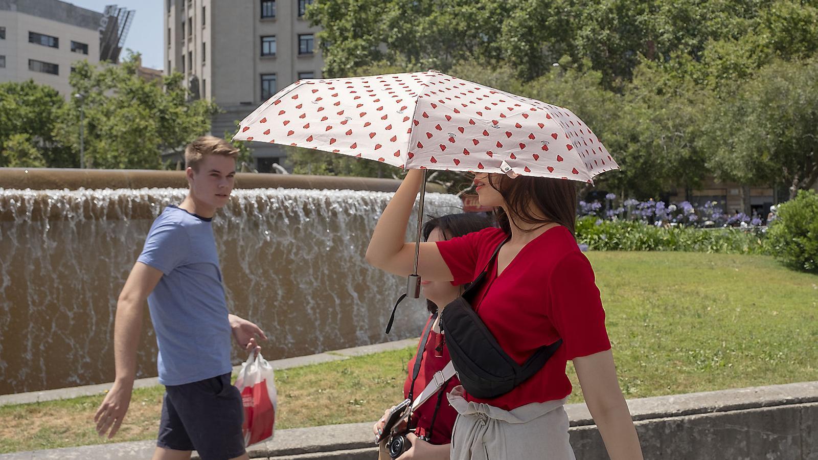 Una persona protegiéndose del sol a la plaza Cataluña de Barcelona durante una oleada de calor el 2020.