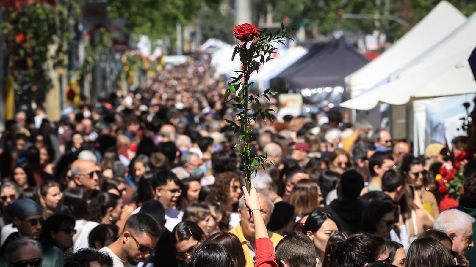 Una persona levanta una rosa en medio de la multitud en el paseo de Gracia