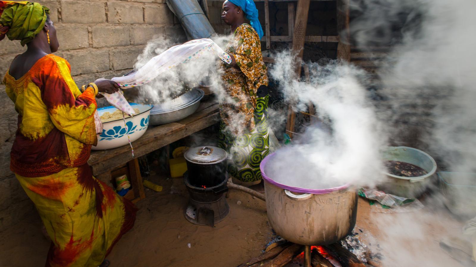 Two women cook rice in a town in Senegal
