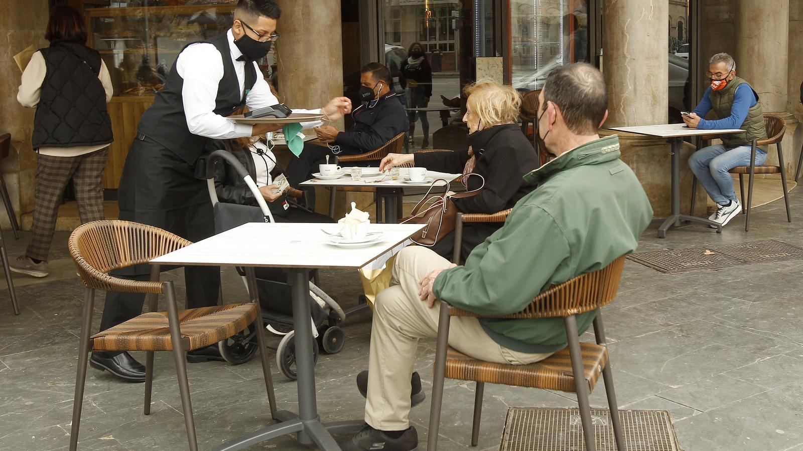 Un cambrer atén diversos clients a la terrassa d'un bar a Palma.