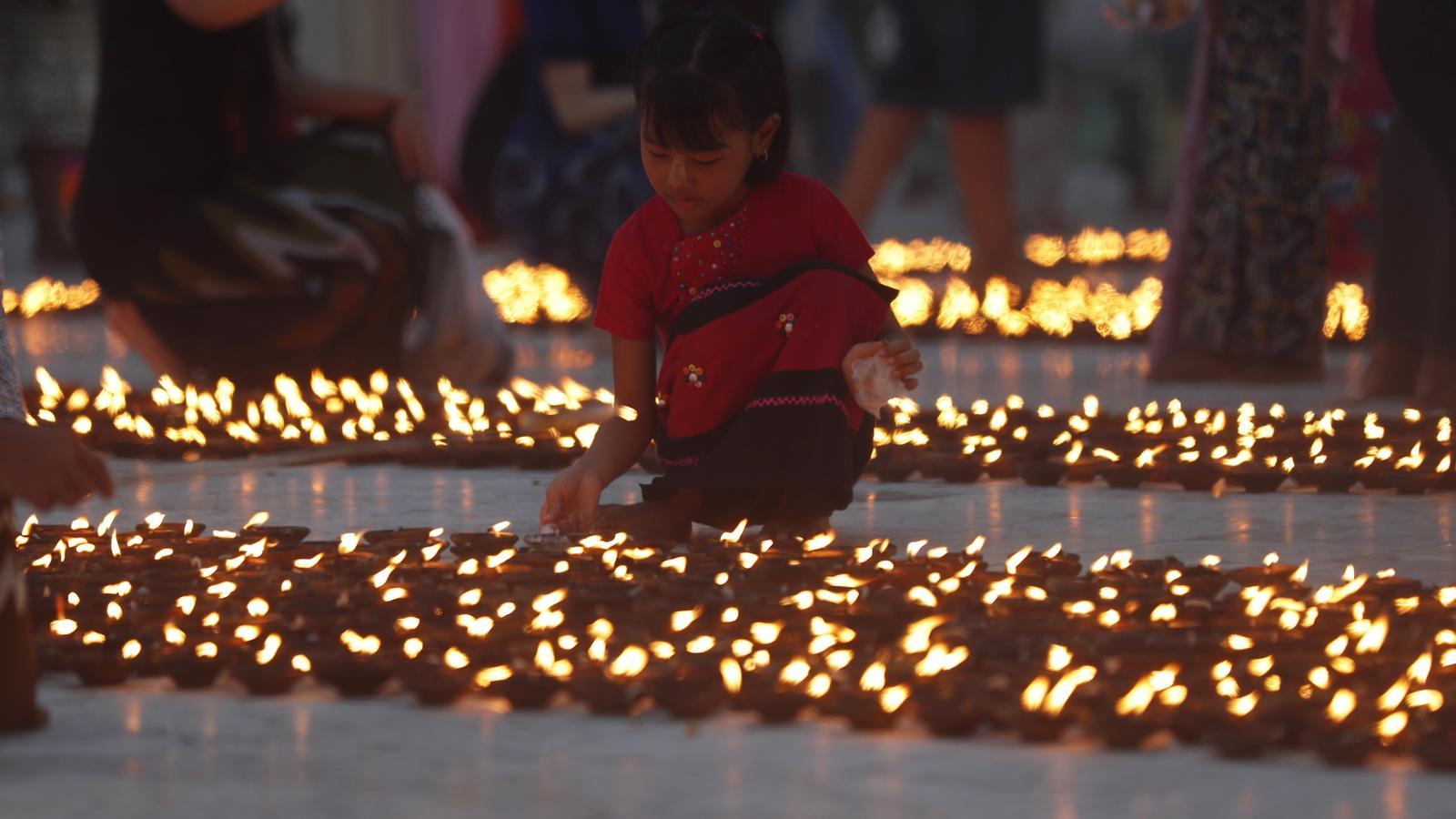 A girl lights oil lamps to offer to Buddha during the Thadingyut festival in Myanmar.