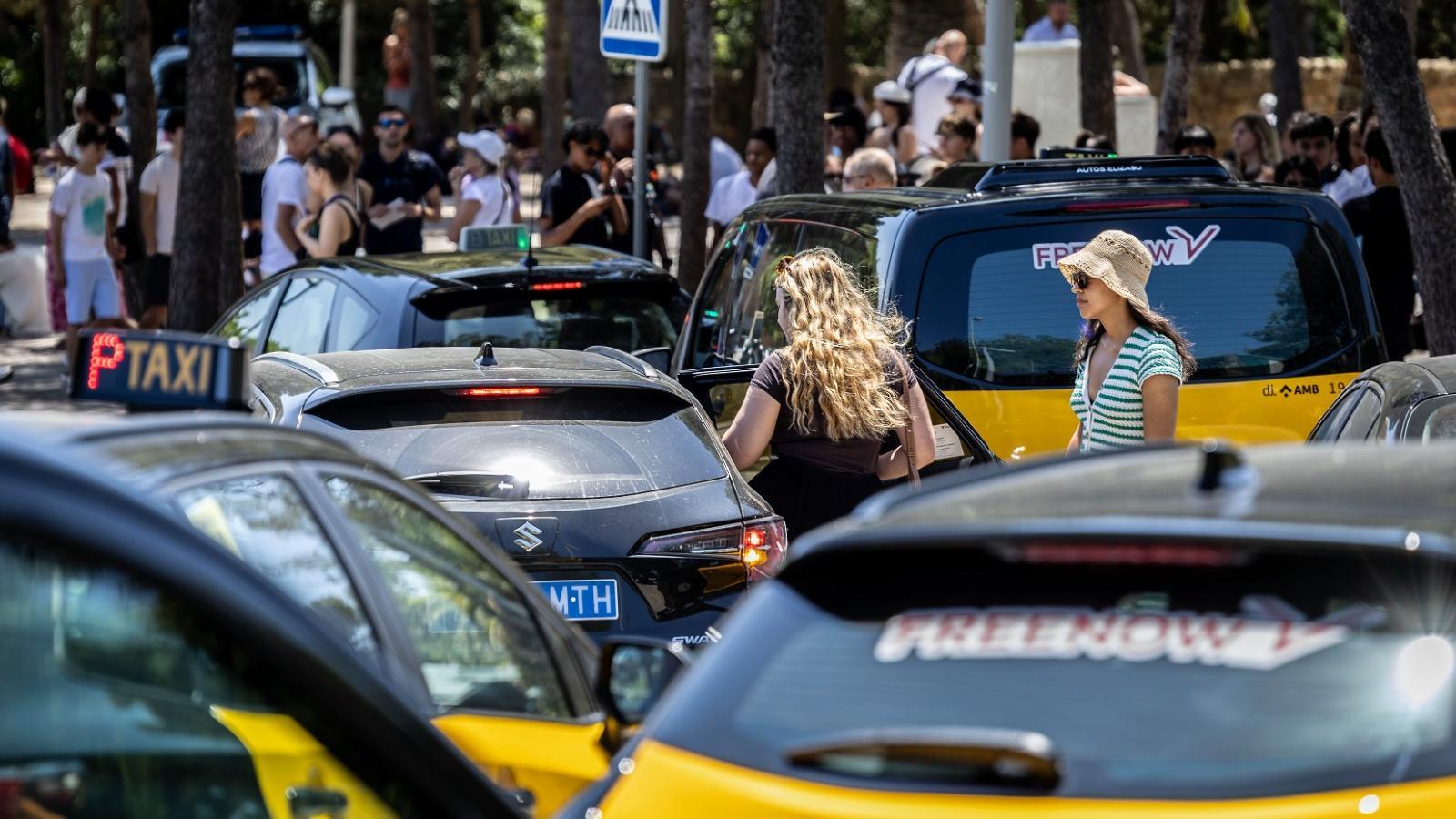 Tourists getting out of a taxi at the stand opposite the entrance to Park Güell on the busy Carmel Highway.