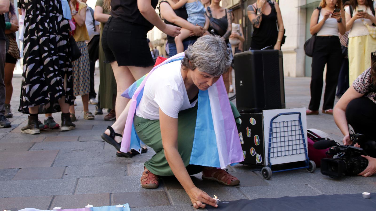 A woman lighting a candle in Girona's Plaça del Vi in memory of the victim