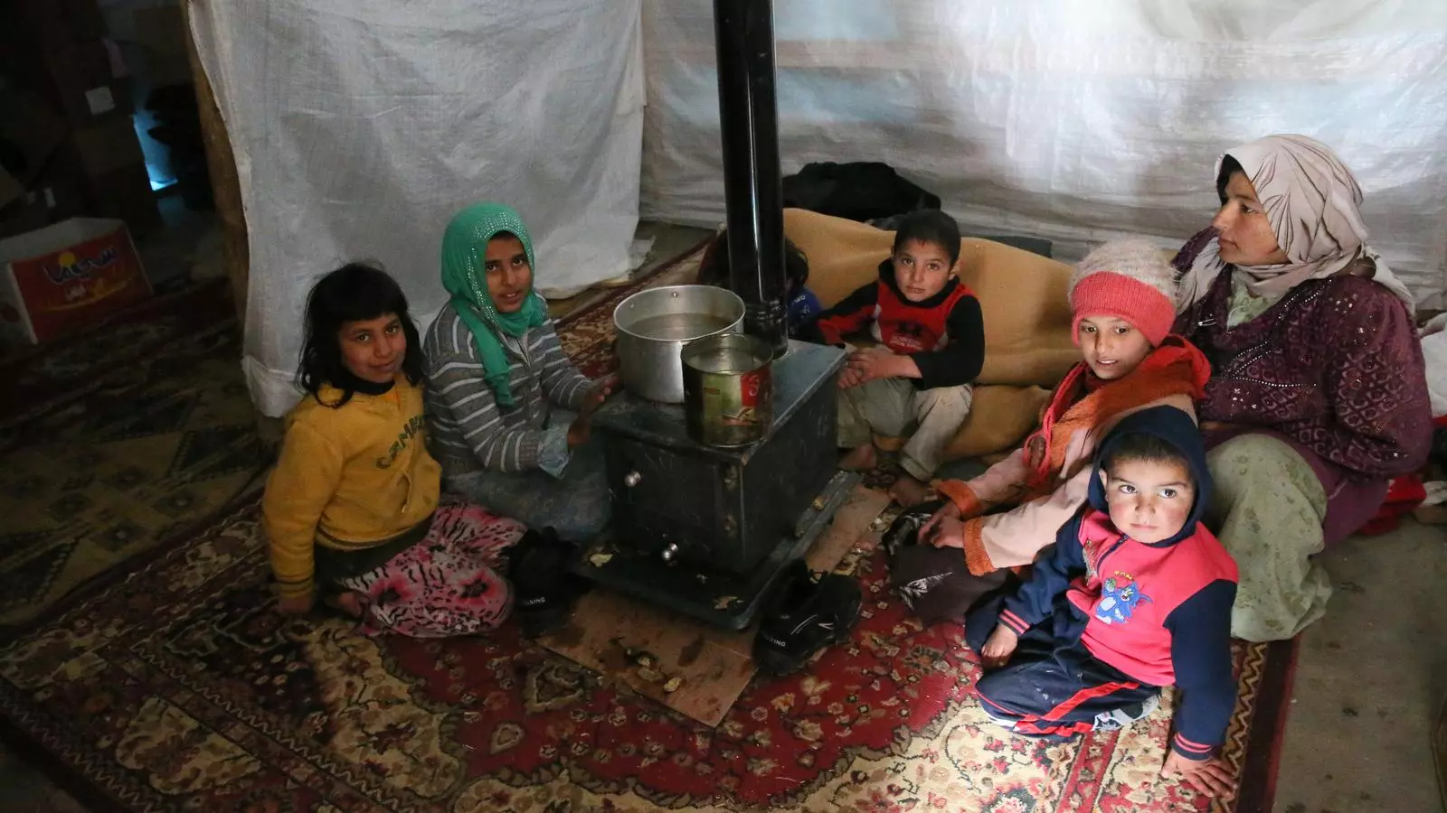 Una família de refugiats de Síria, incloent-hi Ghalia A l'Moustafa 11 anys d'edat (segon per l'esquerra), s'escalfen en una estufa a la seva botiga de campanya a l'assentament de tendes de Talk Sharon a la vall de Bekaa.