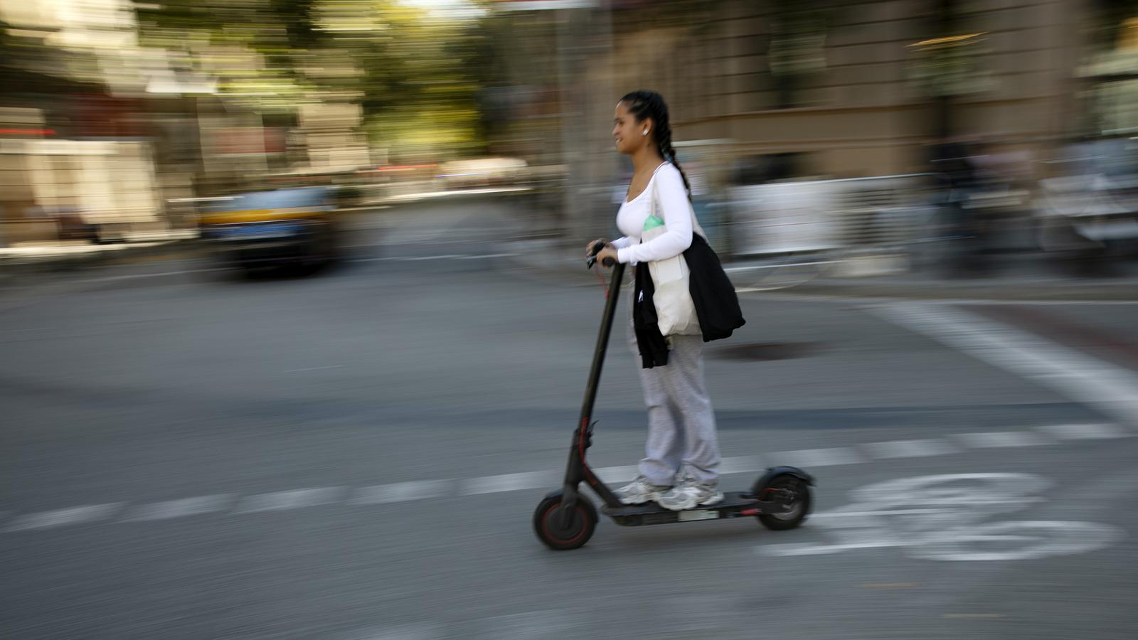 Una chica circulando en patinete por Barcelona.