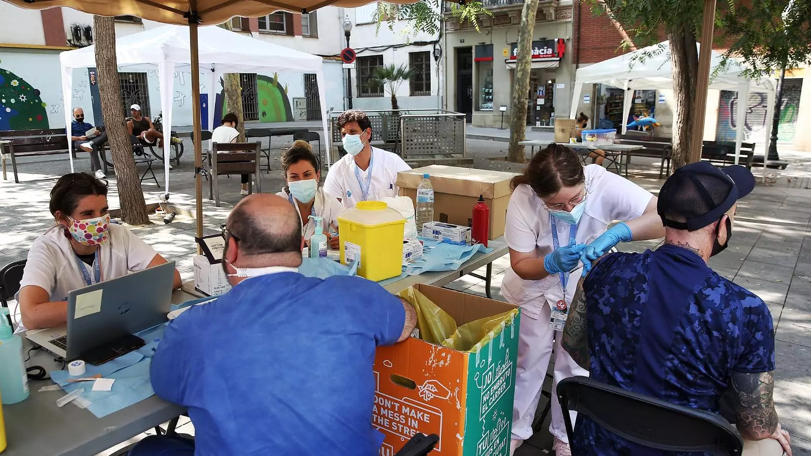 Una enfermera vacunando un hombre, en su punto móvil situado en la plaza del Surtidor del Pueblo-seco de Barcelona
