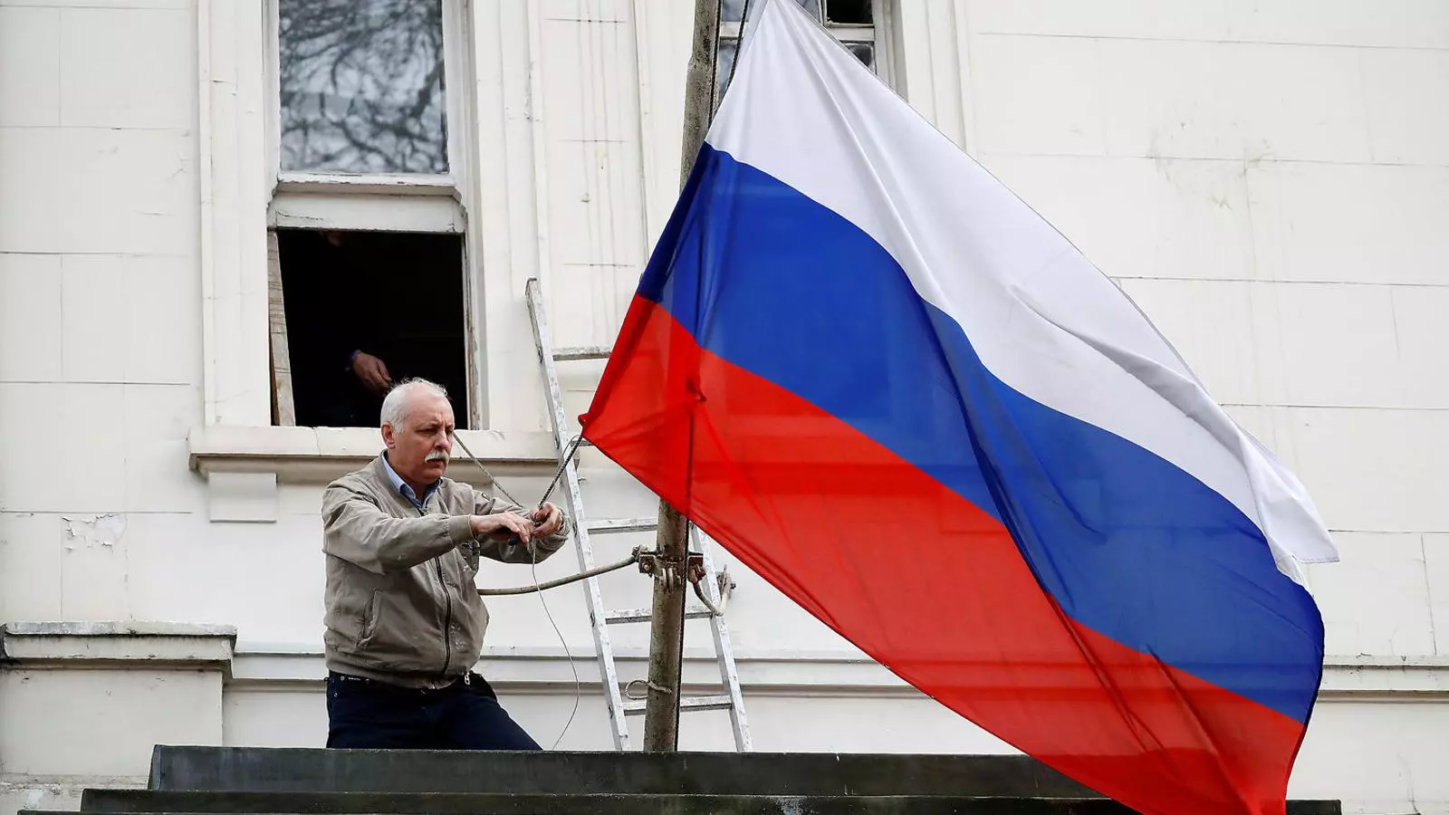 Un treballador de l’ambaixada russa a Londres retirant ahir la bandera de la Federació de l’exterior de l’edifici.