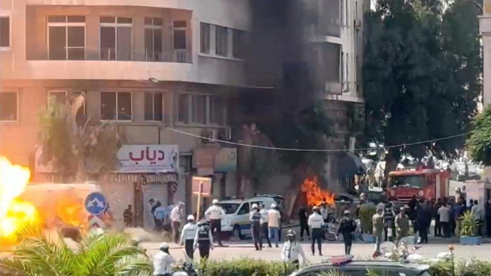 Efectivos de los servicios de emergencia trabajan mientras se elevan el humo y las llamas en el lugar donde estallaron artefactos explosivos, cerca de un hotel donde se debía alojar el presidente francés, Emmanuel Macron, en Damasco