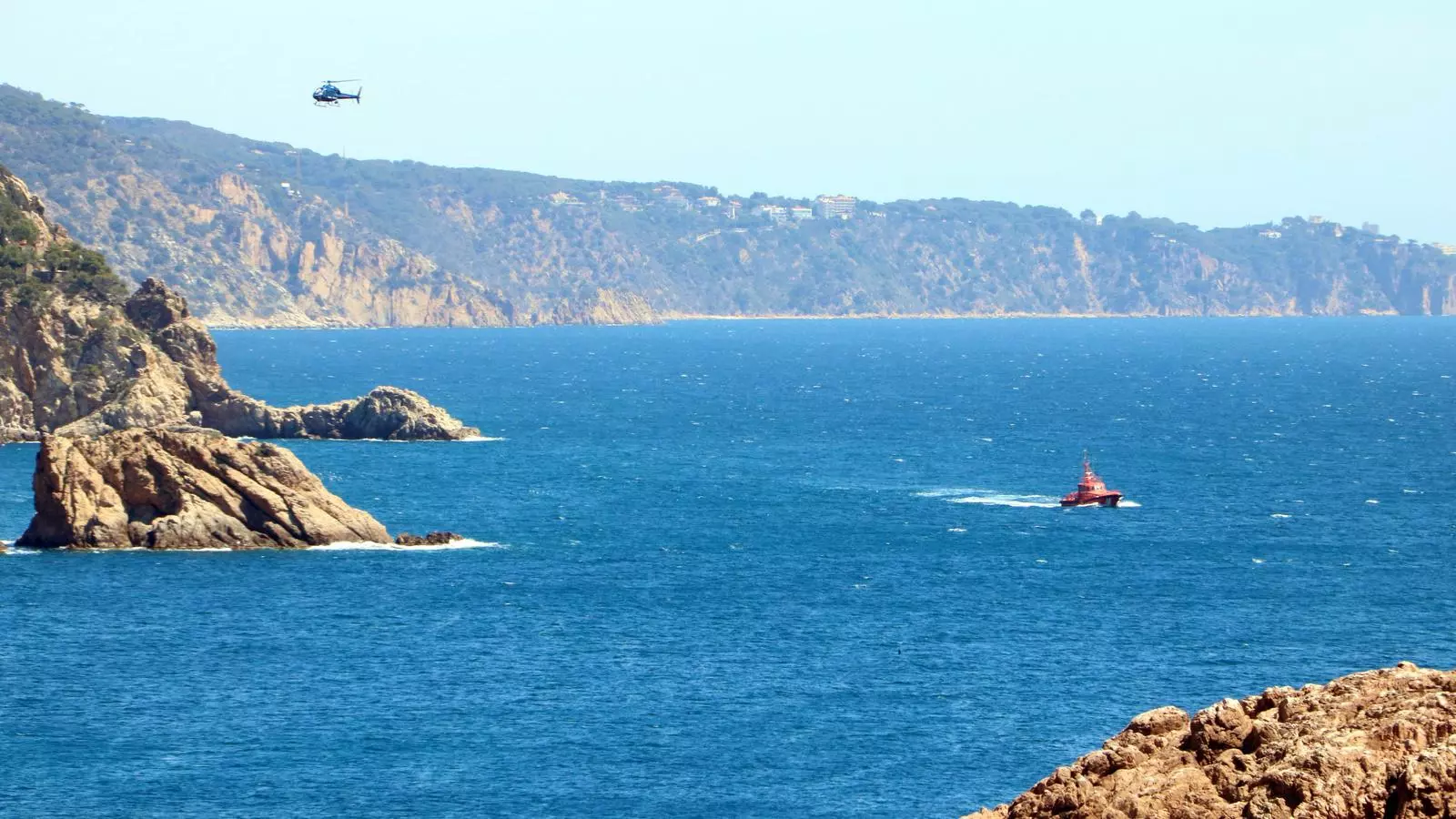 Una embarcació de Salvament Marítim i un helicòpter buscant l'home desaparegut