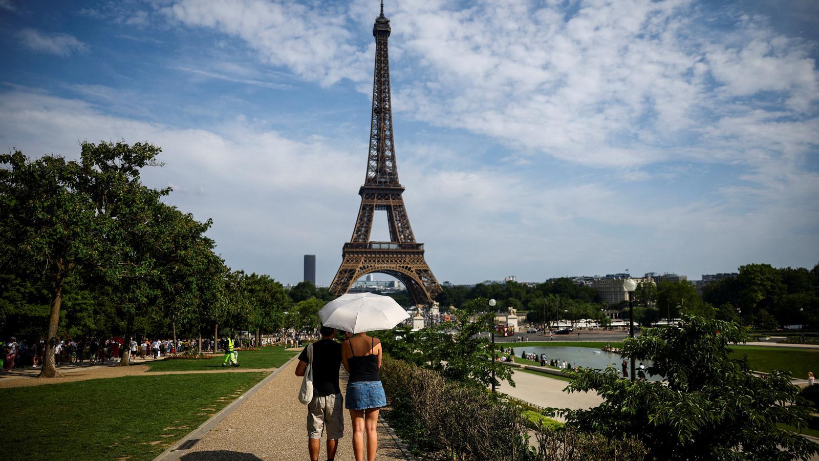 A couple shields themselves from the sun under an umbrella near the Eiffel Tower, as temperatures rise in Paris during a second heatwave affecting a large part of France. /Archive.