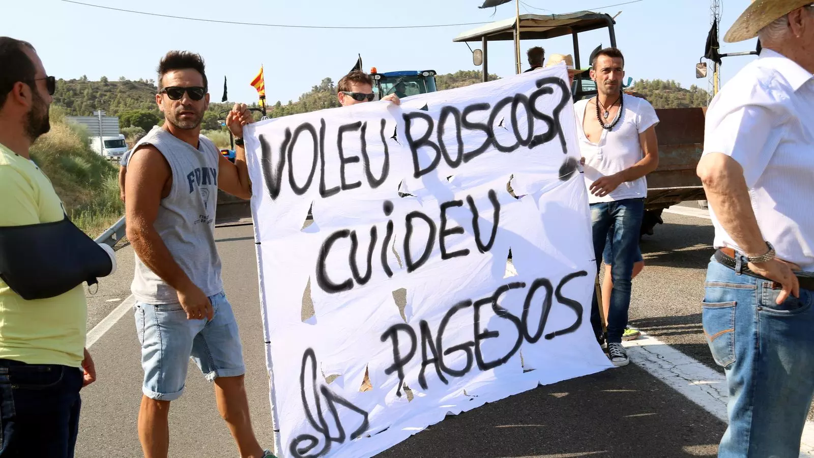 Els afectats pel foc de la Ribera d'Ebre protesten per reclamar ajuts a fons perdut. A la imatge, un grup de pagesos tallant la carretera C-12 a Flix amb una pancarta que reclama un millor tracte per al sector.