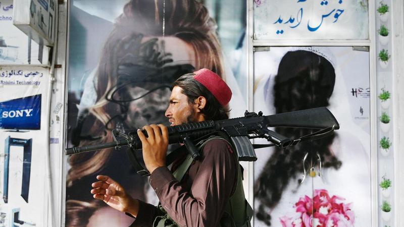 Un combatent talibà passa per davant d’un saló de bellesa amb imatges de dones pintades amb un aerosol a Shar-e-Naw a Kabul