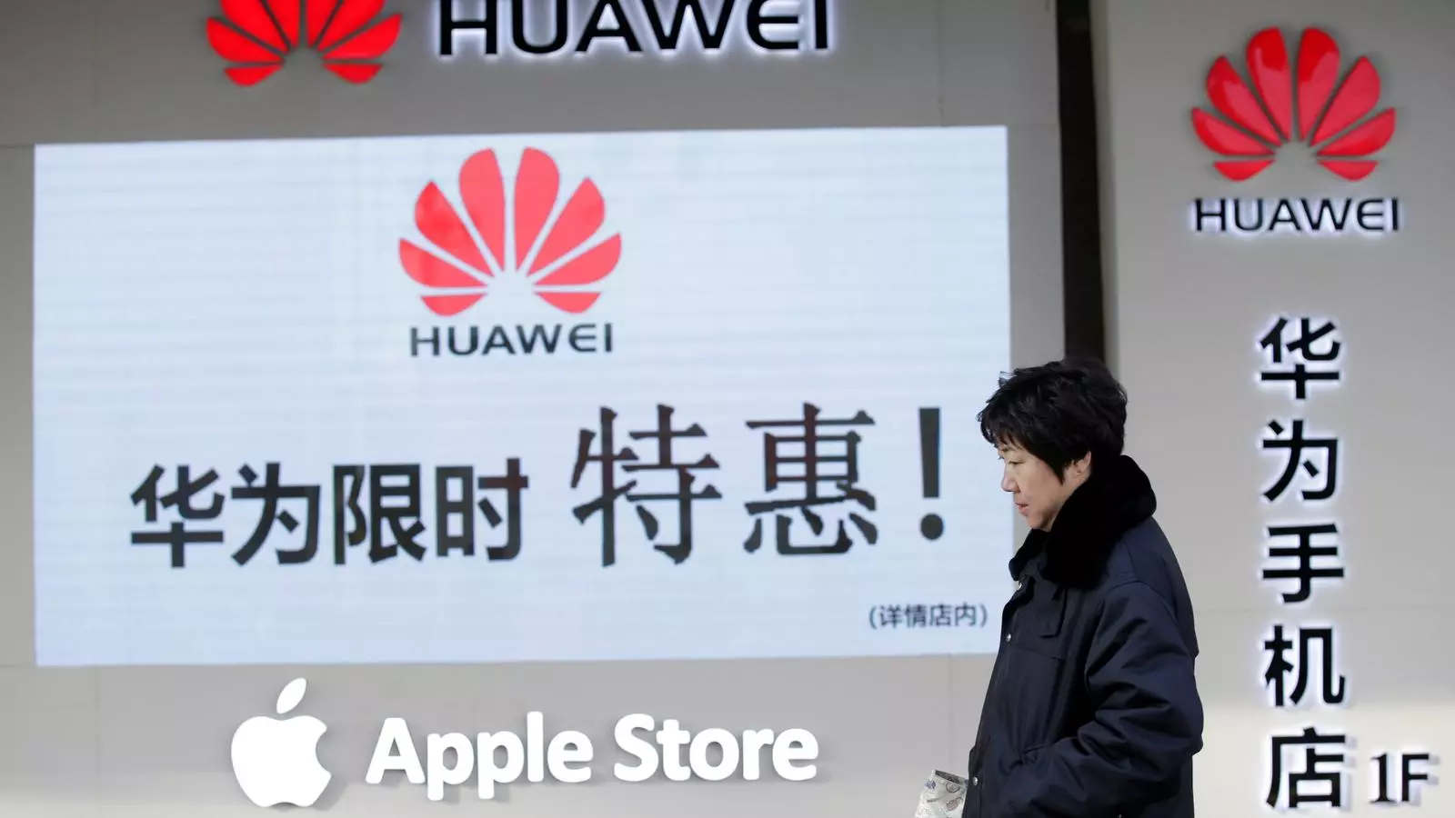 Una dona camina per davanat de la botiga de Huawei i Apple de Pequín.