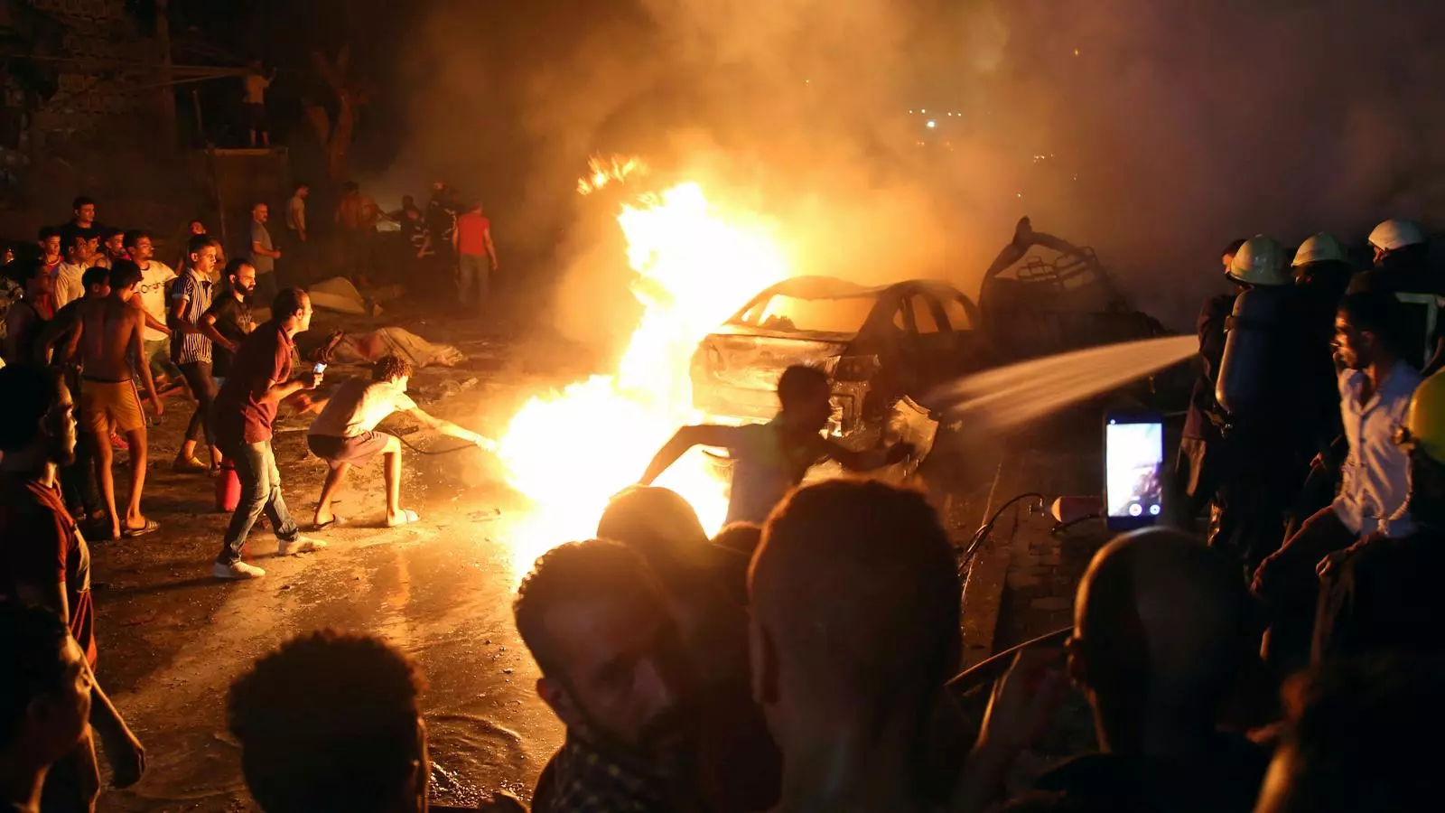 Un grup de persones intenta apagar les flames provocades per l'explosió aquest dilluns a El Caire.