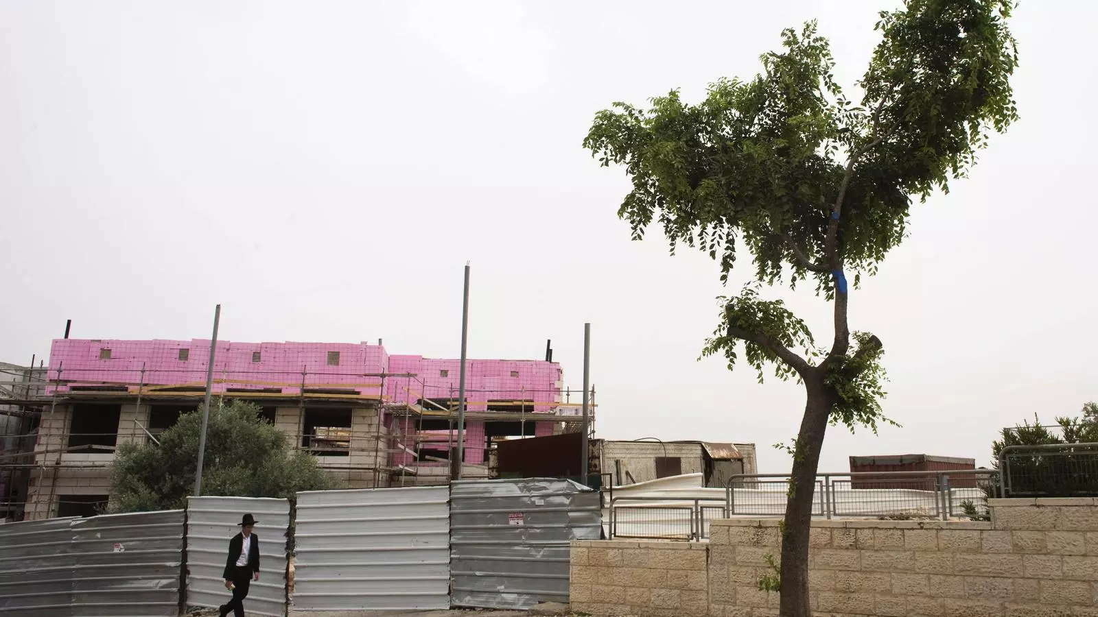 Un ultra-ortodox passa per davant de les obres d'un edifici en un assentament a Jerusalem. RONEN ZVULUN / REUTERS