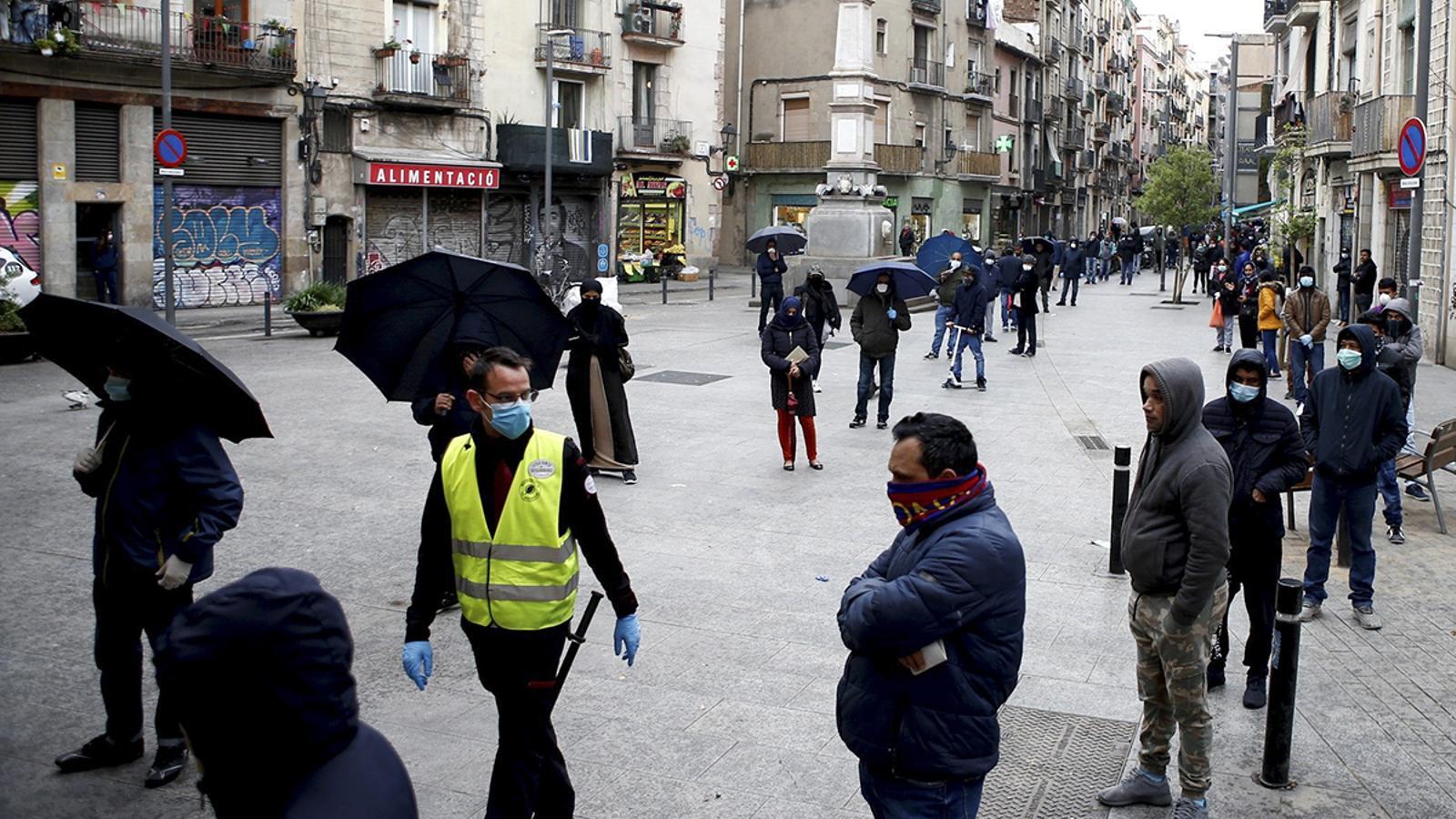 Desenes de persones fent cua a l'oficina del Centre de Serveis Socials del barri del Raval