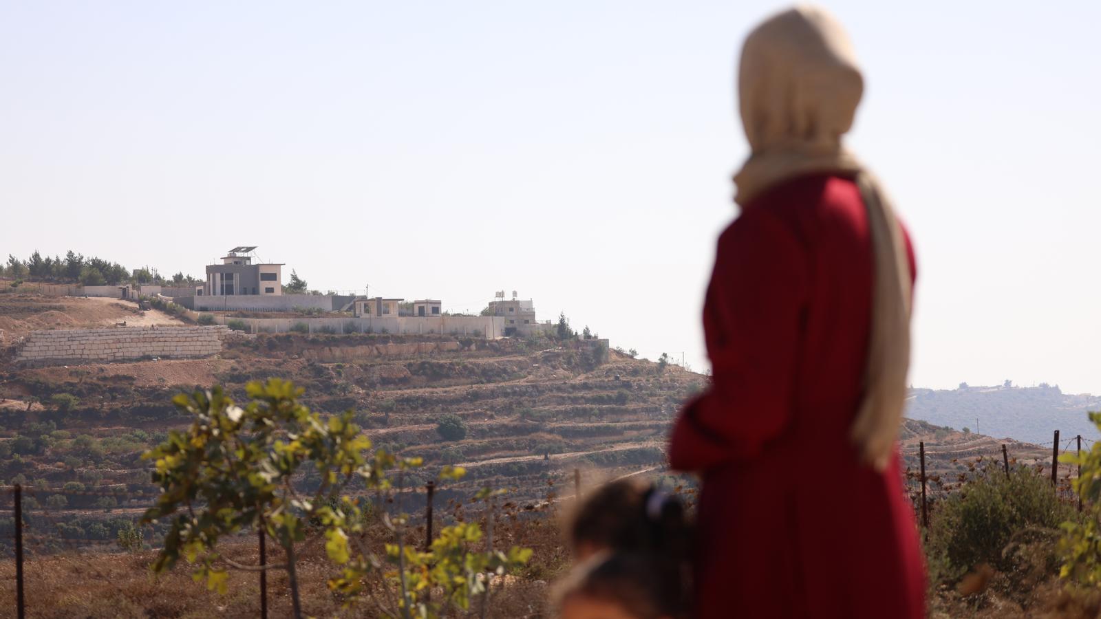The Palestinian Refqa Hassan watches as Israeli settlers besiege her family's house for the fourth consecutive day in the city of Qusra, south of Nablus, on August 12, 2026.