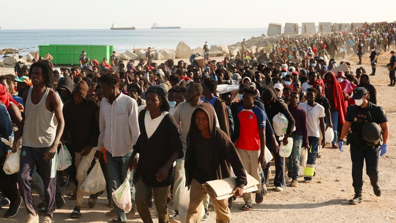 Migrants are escorted from a makeshift camp on the beach to official shelters in Ceuta