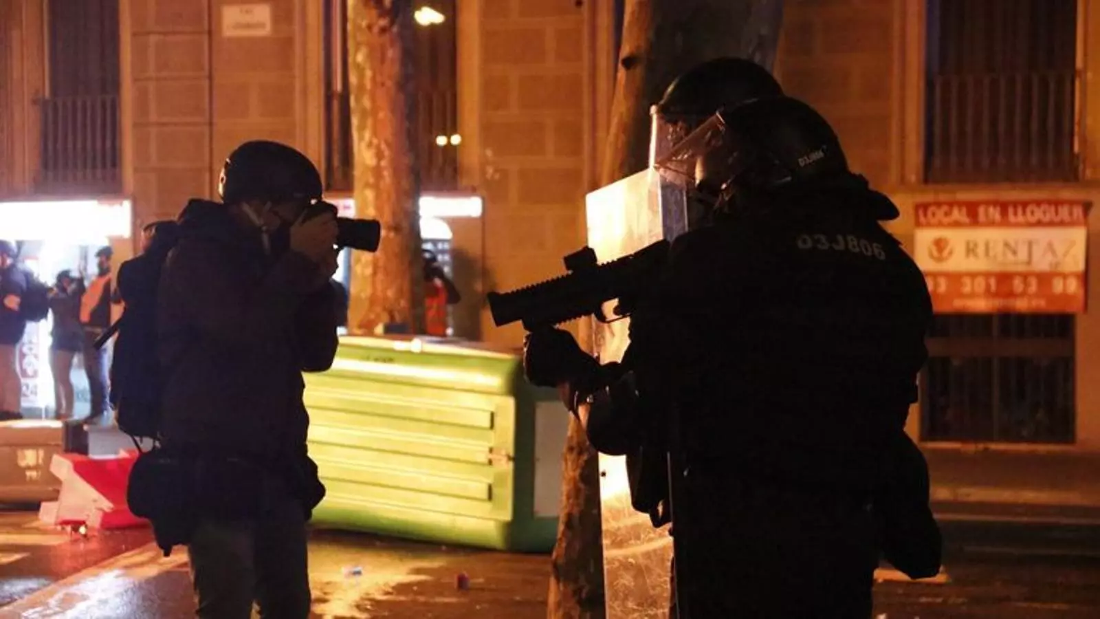 Dos escopeters dels Mossos d'Esquadra amb llançadores foam davant d'un fotoperiodista durant les protestes en suport a Pablo Hasél a Barcelona