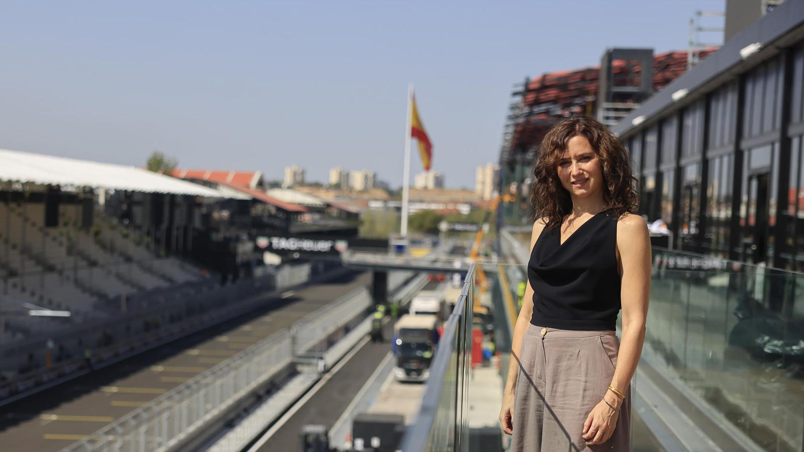 Isabel Díaz Ayuso at the Madrid urban circuit with the large Spanish flag in the background.